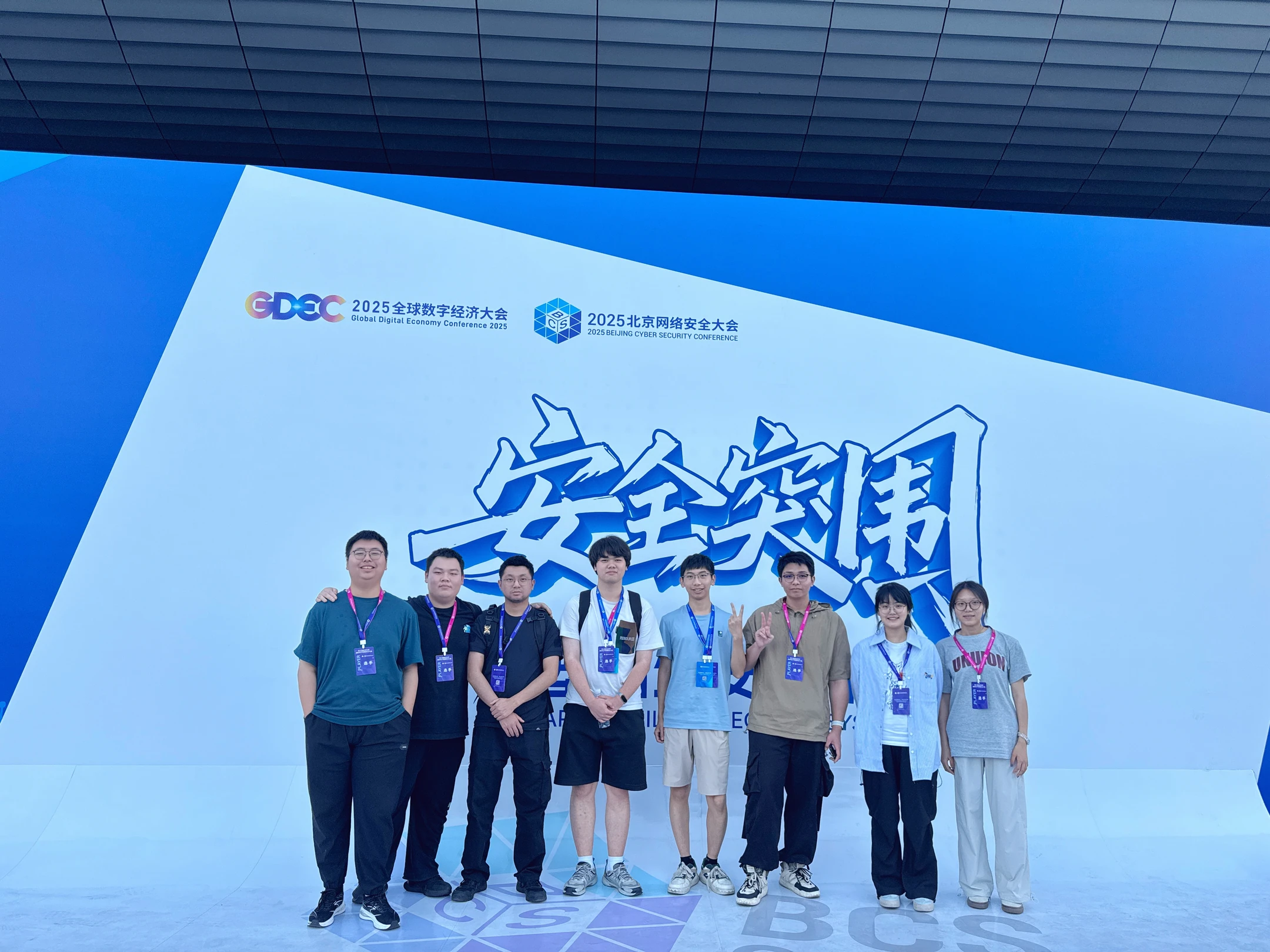 八位队员在2025北京网络安全大会安全突围背景板前合影