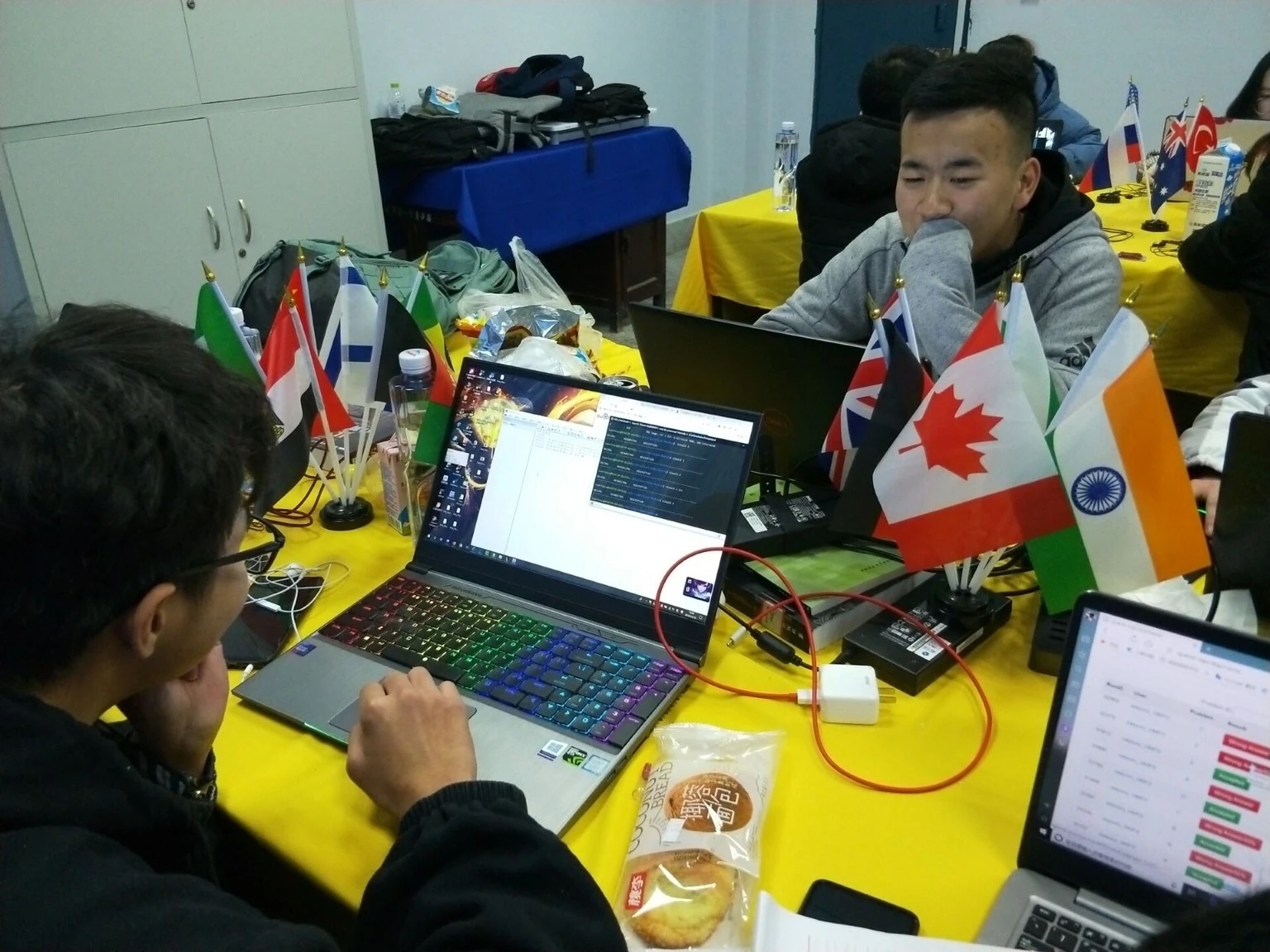 2018 年周赛，队员围坐在黄色桌布的桌前操作电脑